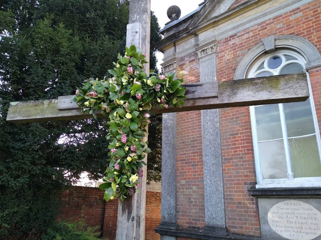 Outside cross covered with greenery and flowers